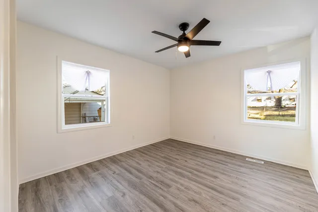 a view of empty room with wooden floor and window