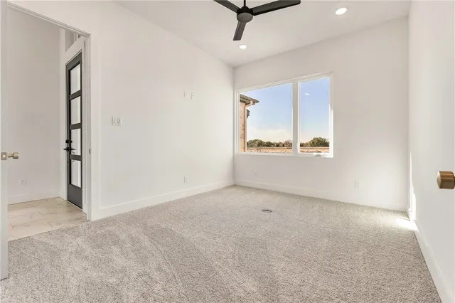 an empty room with windows and ceiling fan