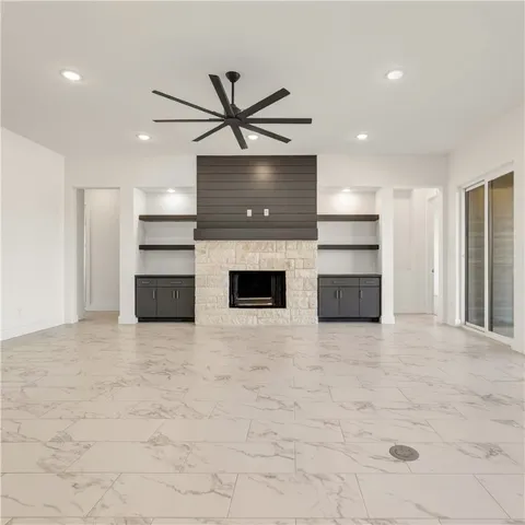 a view of an empty room with a window and a kitchen