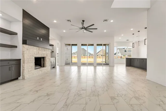 a view of an empty room with kitchen and fireplace