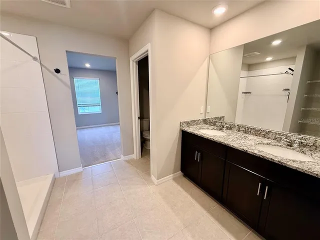 a bathroom with a granite countertop shower and a toilet