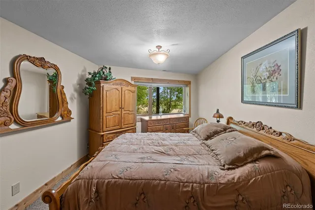 a bedroom with a bed a mirror on the dresser and a window