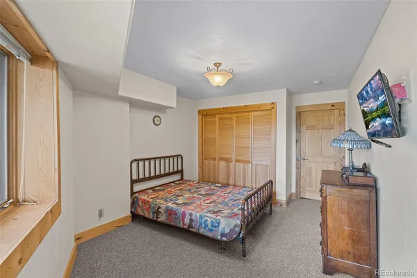 a bedroom with a bed table flat screen tv and a window