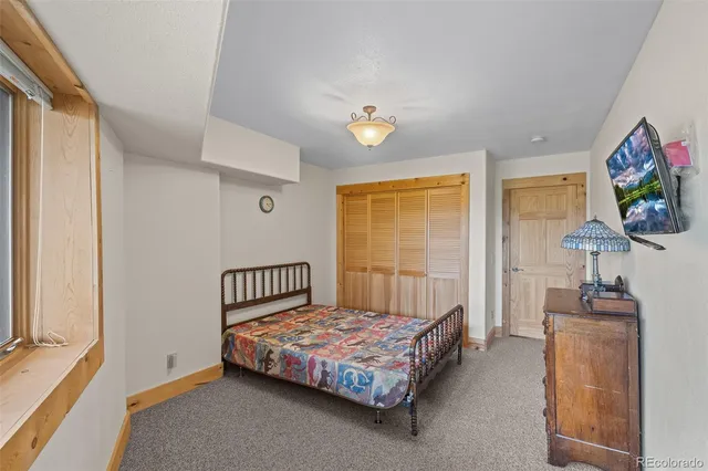 a bedroom with a bed table flat screen tv and a window