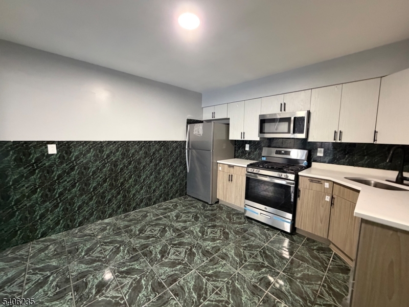 327 Bond Street Elizabeth Port, NJ 07206 - Photo 9 of 22 a kitchen with granite countertop white cabinets and stainless steel appliances
