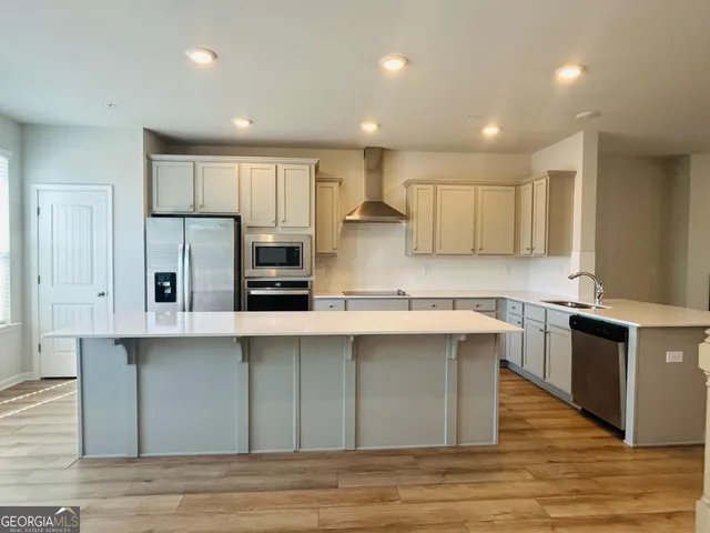 a kitchen with stainless steel appliances granite countertop a stove a sink dishwasher and a refrigerator with wooden floor