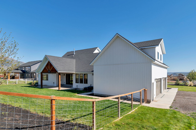 1820 West Farmhouse Flats Road Peoa, UT 84061 - Photo 57 of 79 Modern farmhouse exterior with white board and batten siding, dark shingle roof, and a three-car garage