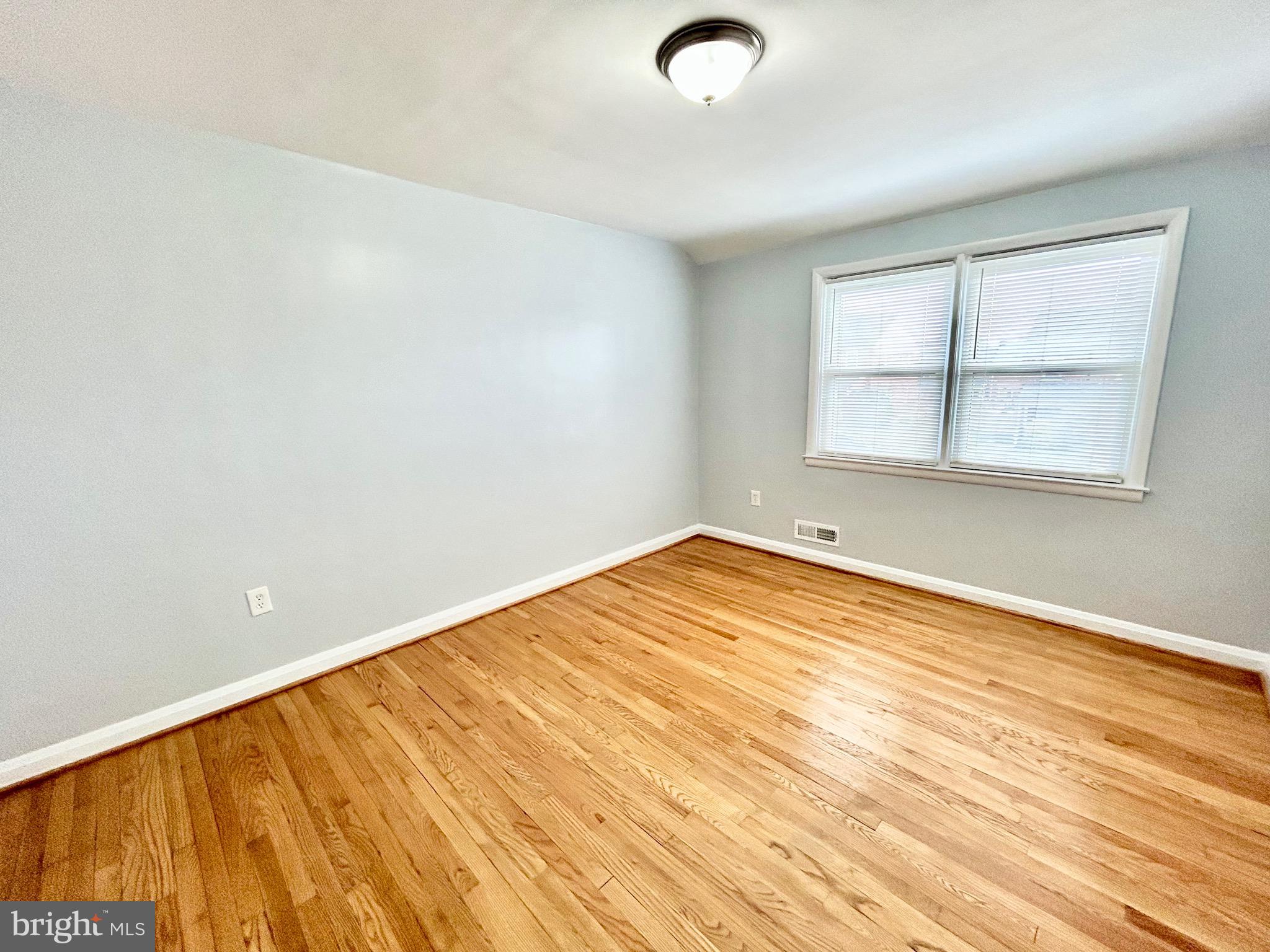 6116 Edlynne Road Baltimore, MD 21239 - Photo 11 of 18 an empty room with wooden floor and windows