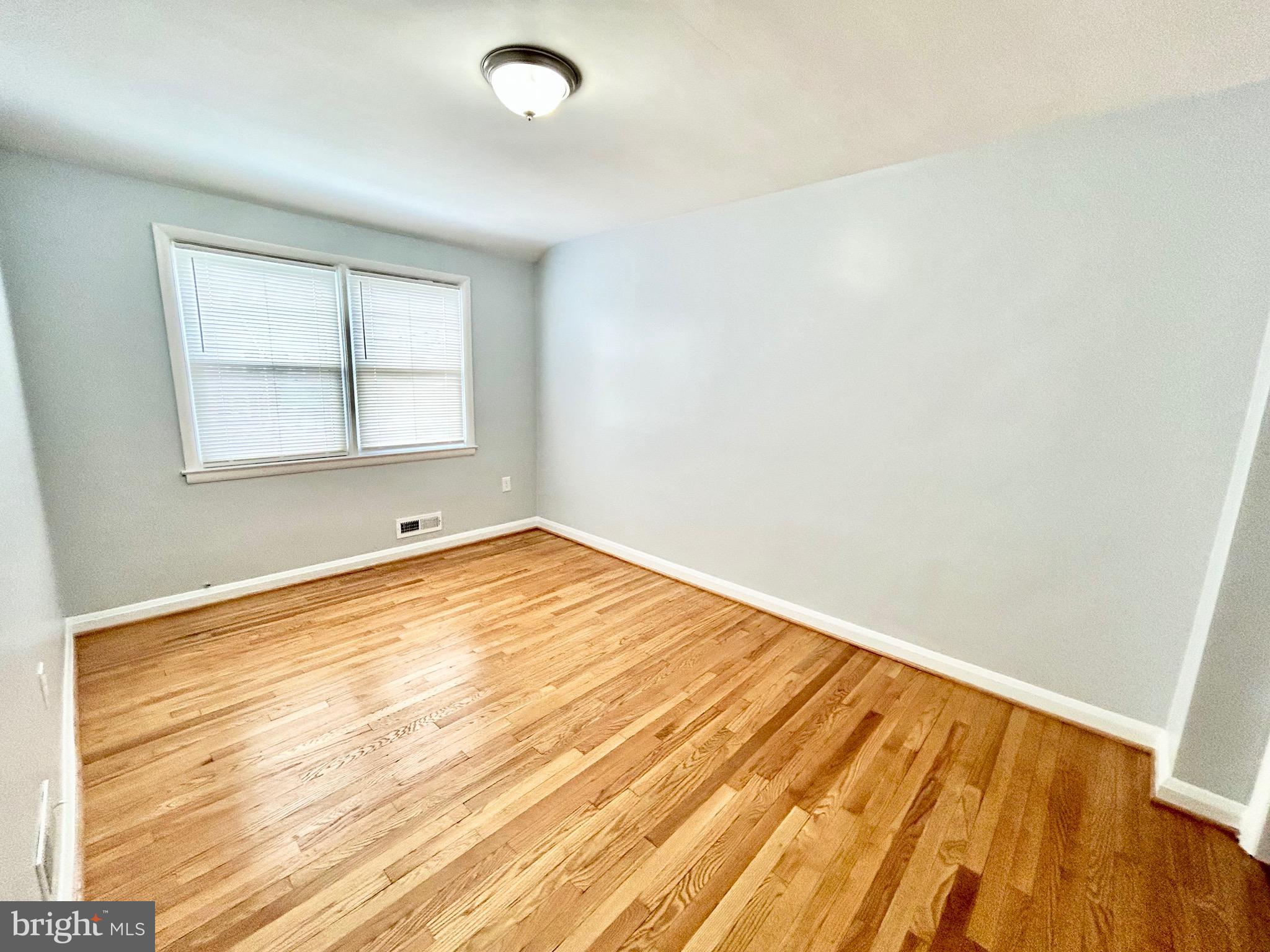 6116 Edlynne Road Baltimore, MD 21239 - Photo 12 of 18 an empty room with wooden floor and windows