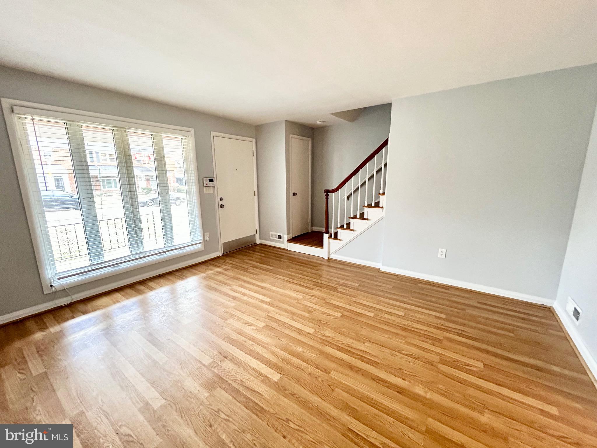 6116 Edlynne Road Baltimore, MD 21239 - Photo 4 of 18 a view of an empty room with wooden floor and a window