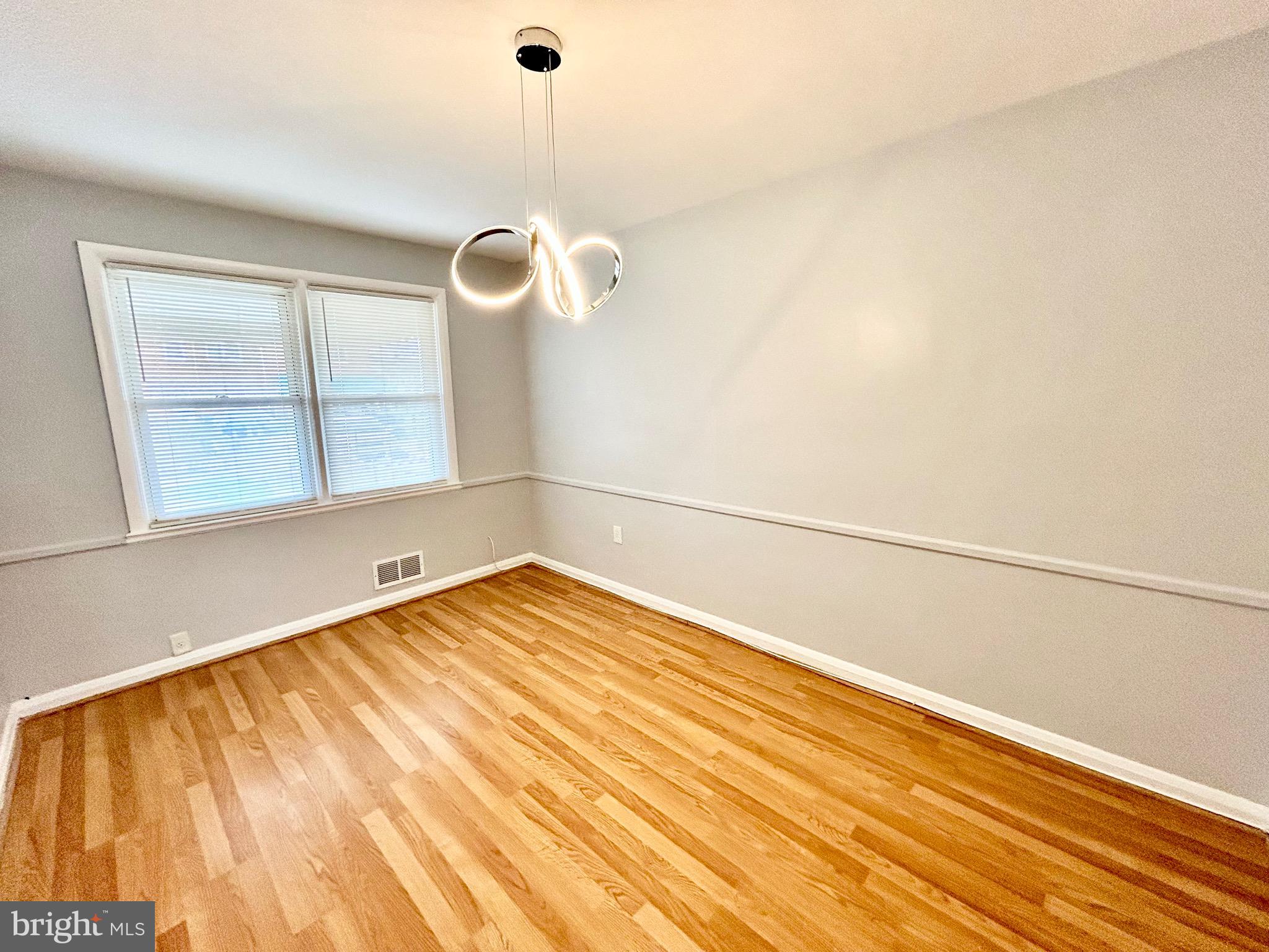 6116 Edlynne Road Baltimore, MD 21239 - Photo 5 of 18 a view of empty room with wooden floor and fan