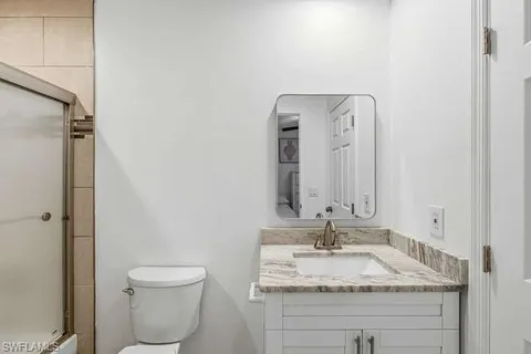 a bathroom with a granite countertop sink toilet and mirror