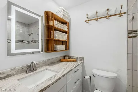 a bathroom with a granite countertop sink toilet and shower
