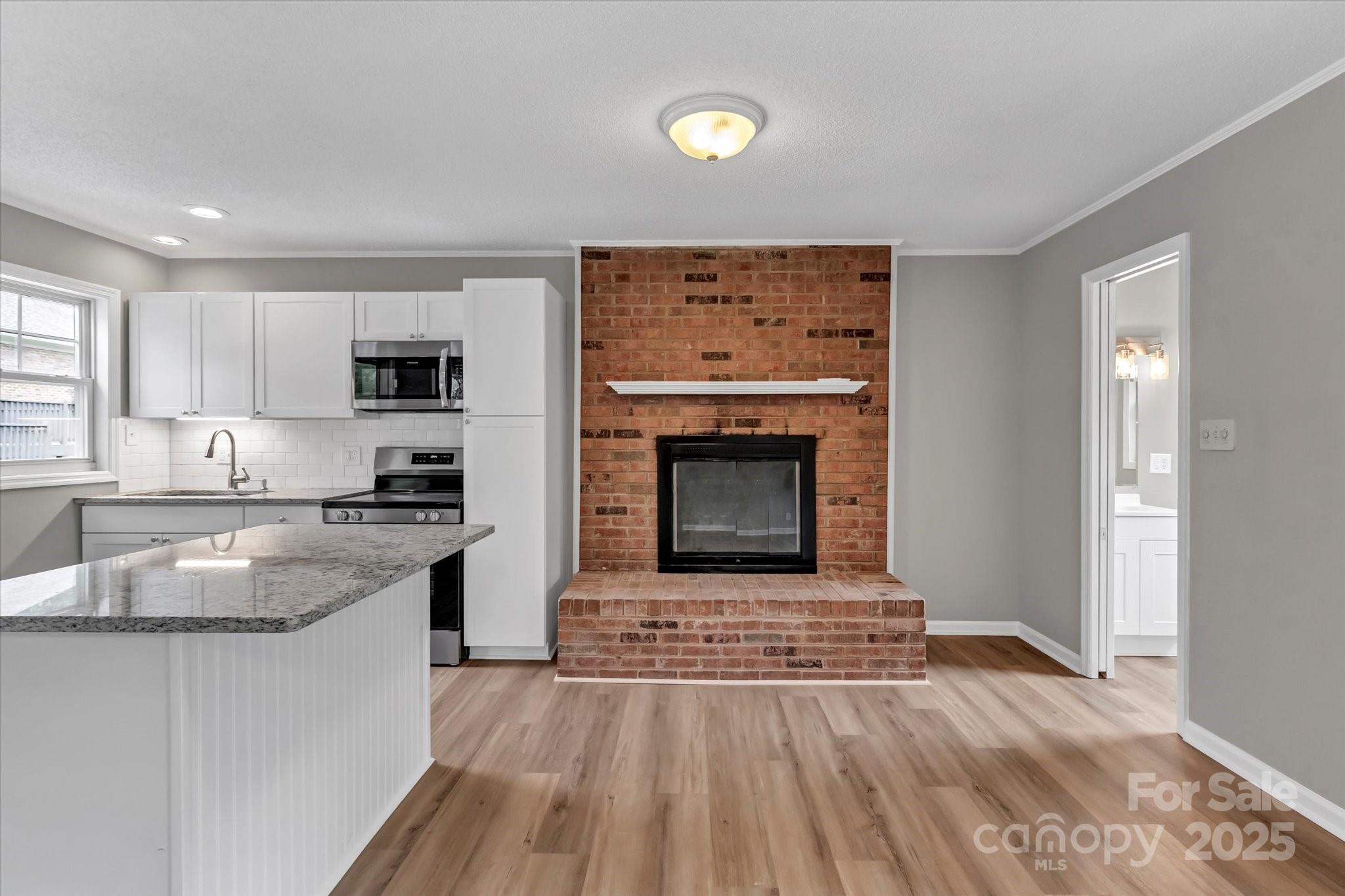 332 East Rebound Road Lancaster, SC 29720 - Photo 24 of 29 a kitchen with granite countertop a stove top oven a sink dishwasher and a fireplace with wooden floor