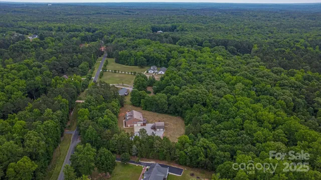 an aerial view of residential house with outdoor space and trees all around