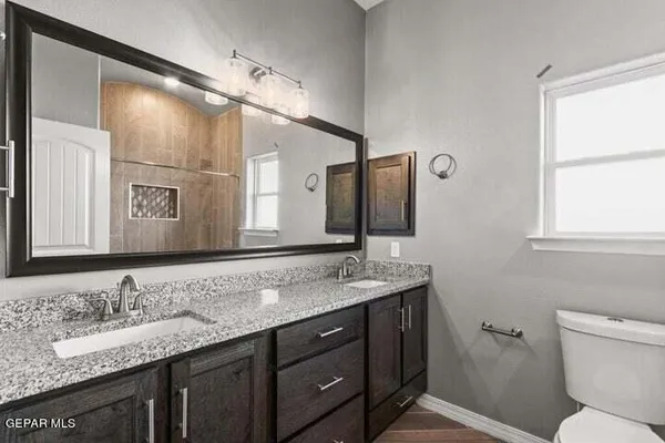 a bathroom with a granite countertop sink mirror and a toilet