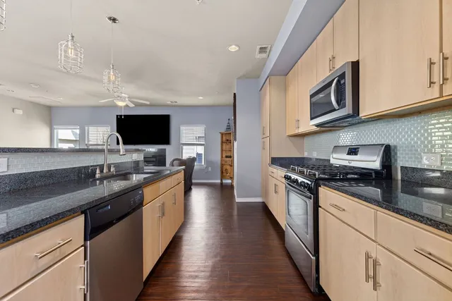 a kitchen with stainless steel appliances granite countertop a sink a stove and a window