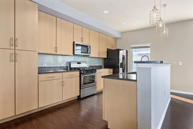 a kitchen with kitchen island a white counter top space stainless steel appliances and cabinets
