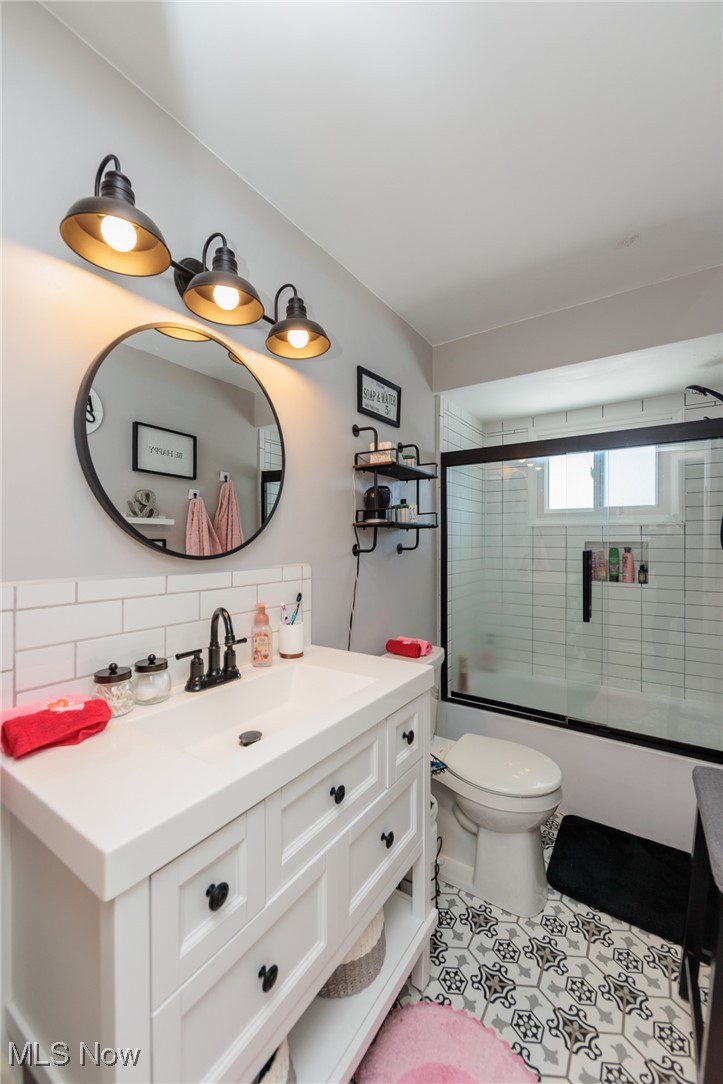 6901 Revere Road Cleveland, OH 44130 - Photo 23 of 50 Full bathroom with toilet, backsplash, tile patterned floors, vanity, and shower / bath combination with glass door