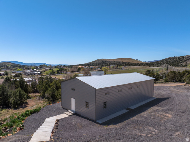 62 North Lucky 7 Road Veyo, UT 84782 - Photo 25 of 43 View of home's exterior featuring a metal roof, a mountain view, an outdoor structure, and a rural view