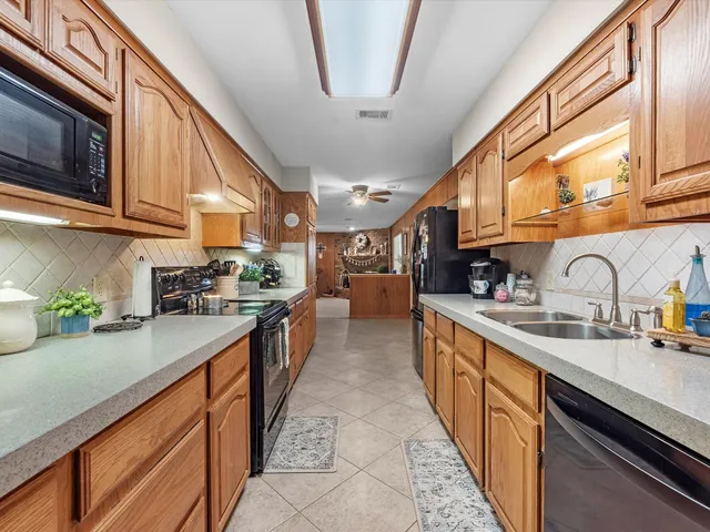 a kitchen with stainless steel appliances granite countertop a sink a stove and a wooden cabinets