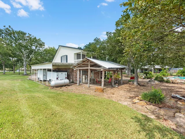 a view of a house with a big yard and large trees