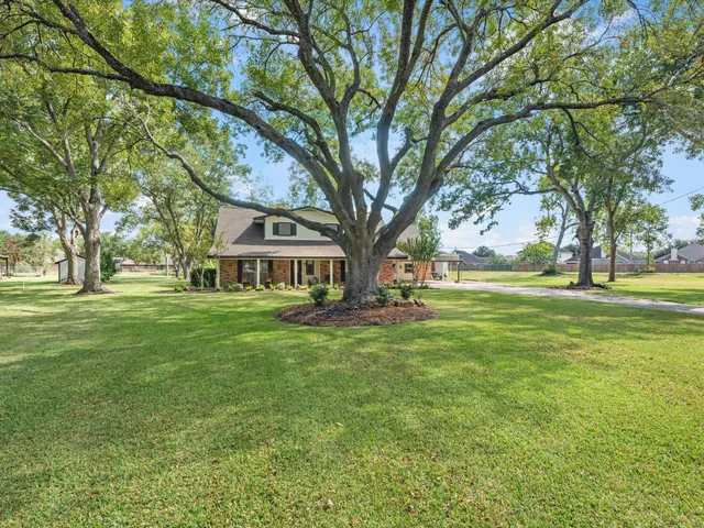 a view of a house with a big yard and large trees