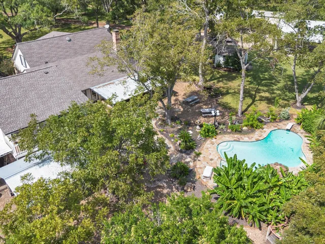 an aerial view of residential house with outdoor space and trees all around