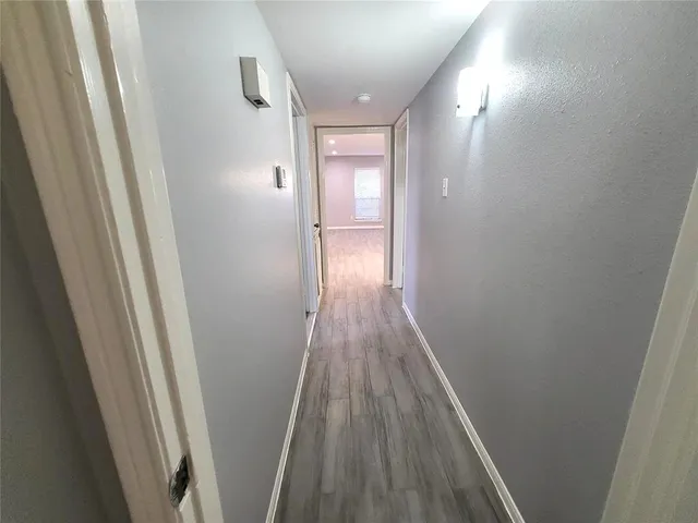 a view of a hallway with wooden floor and a bathroom