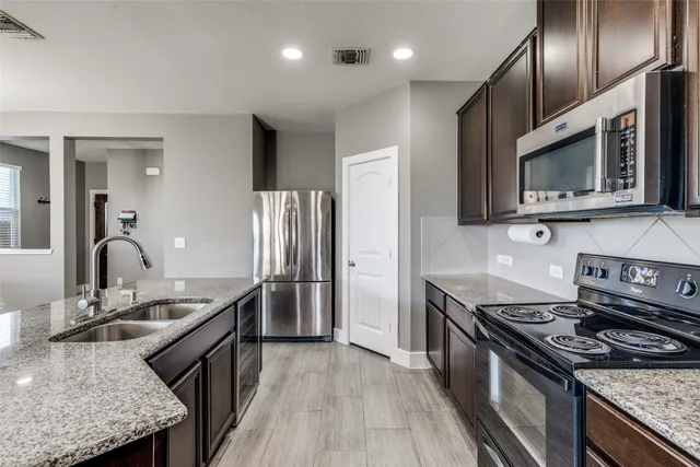 a kitchen with stainless steel appliances granite countertop a sink stove and refrigerator
