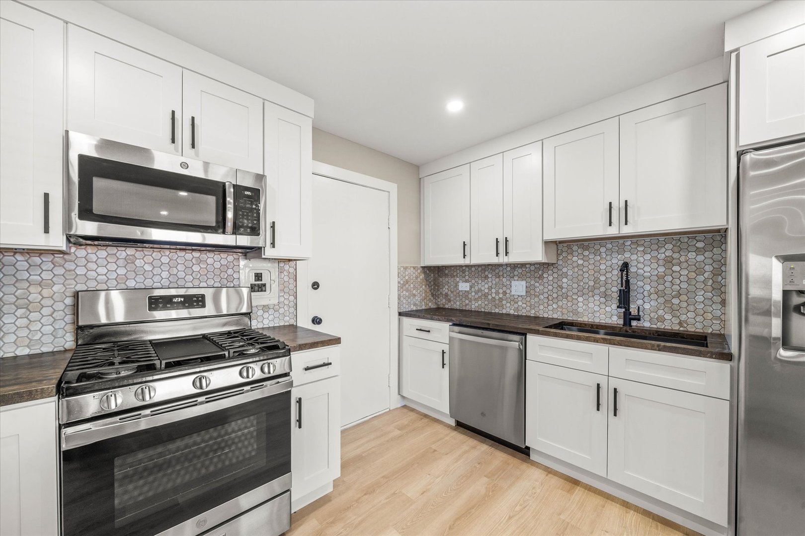 1313 Rebecca Road, Unit 101 Lombard, IL 60148 - Photo 7 of 18 a kitchen with granite countertop a stove top oven microwave and cabinets