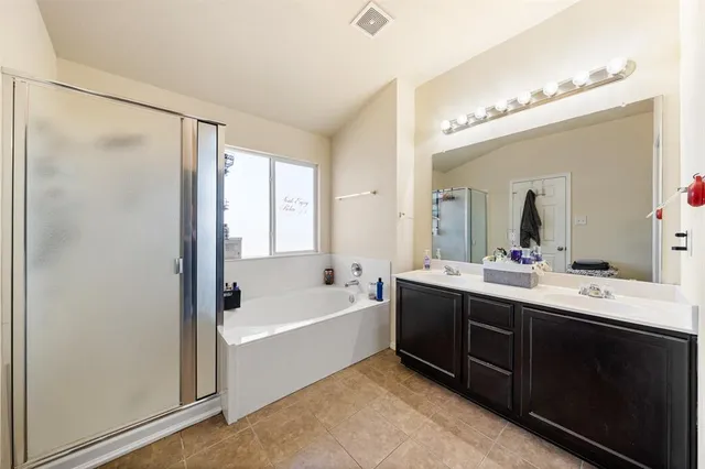 a spacious bathroom with a tub sink shower and mirror