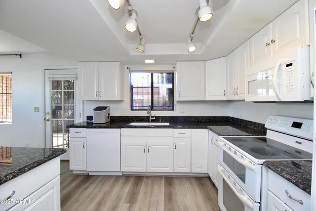 a kitchen with granite countertop white cabinets and white appliances