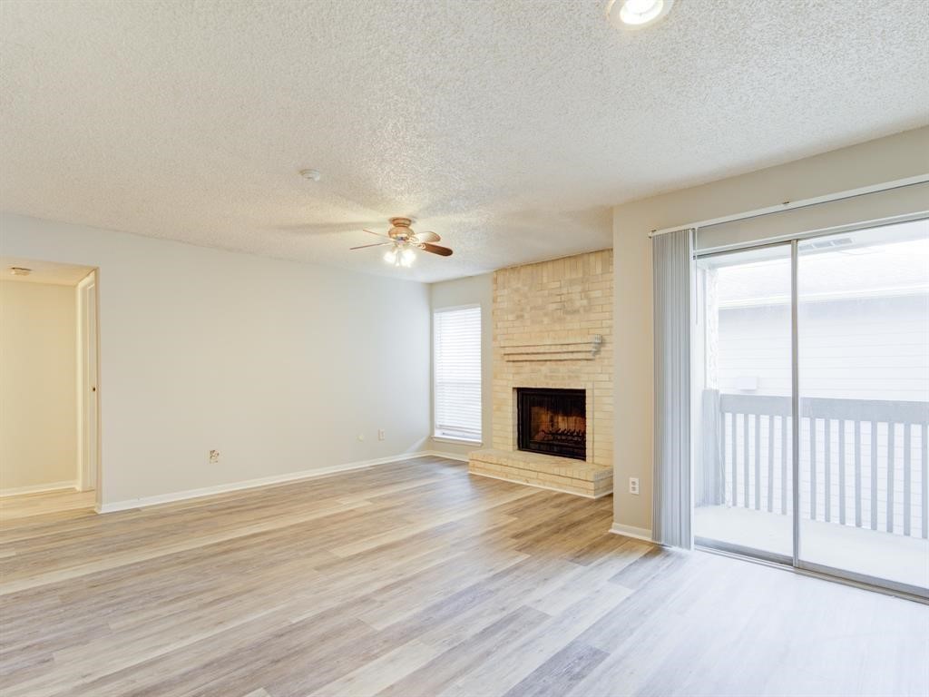 an empty room with wooden floor fireplace and windows