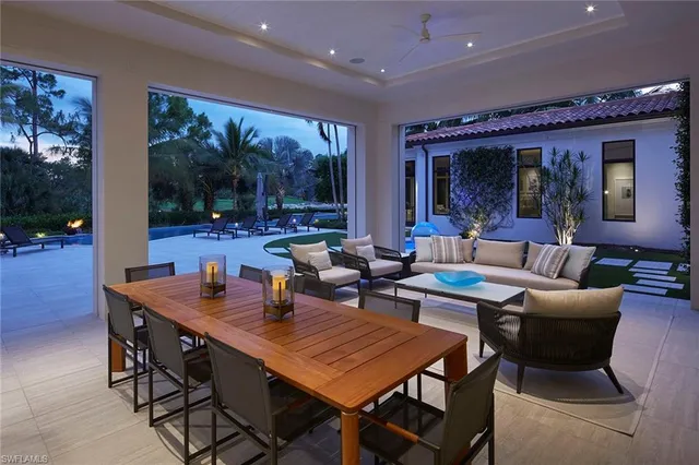 a dining hall with stainless steel appliances kitchen island granite countertop a table chairs and a refrigerator