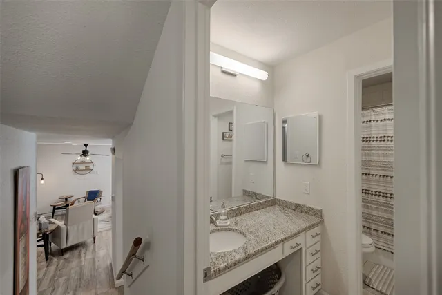 a bathroom with a granite countertop sink a mirror and shower