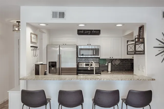 a kitchen with stainless steel appliances kitchen island granite countertop a table and chairs in it