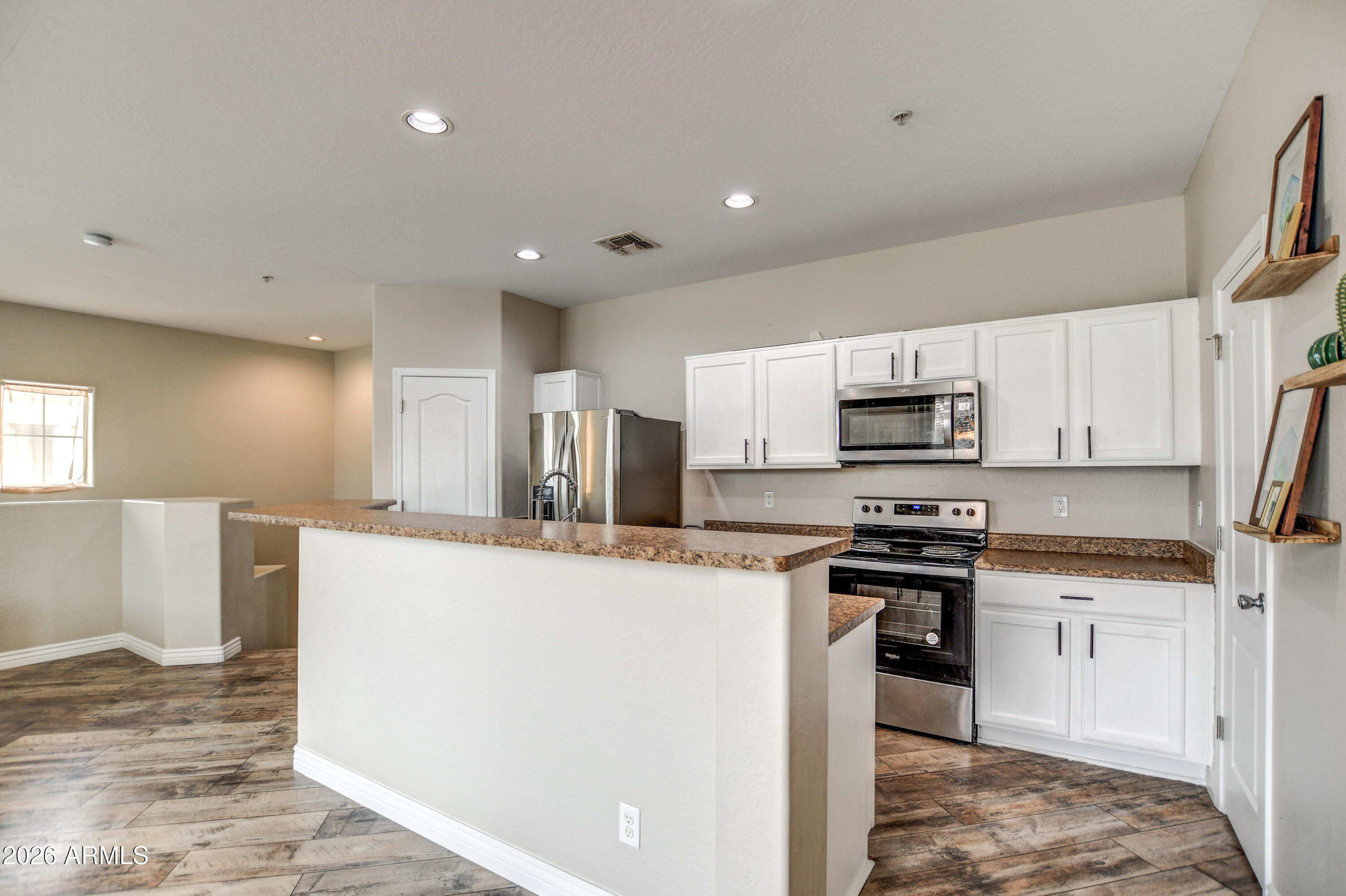7515 South 30th Place Phoenix, AZ 85042 - Photo 4 of 23 a kitchen with stainless steel appliances a stove top oven a sink a refrigerator white cabinets and wooden floor