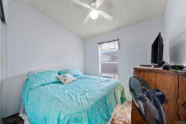 a bedroom with a bed and a flat tv screen on the dresser