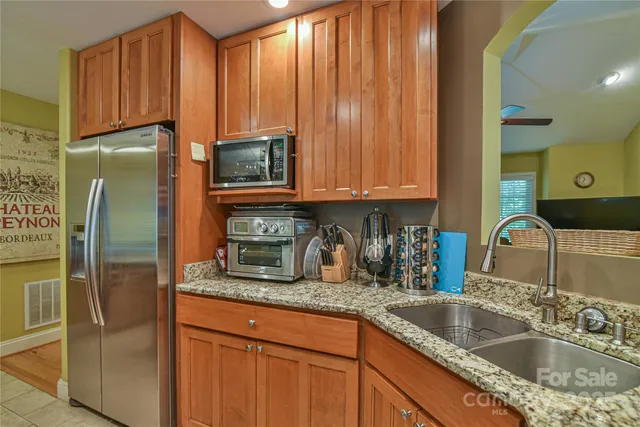 a kitchen with granite countertop stainless steel appliances a refrigerator a sink and cabinets