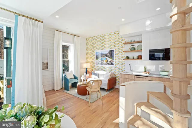 a living room with furniture kitchen view and a wooden floor
