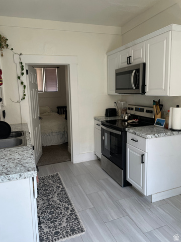 857 27th Street Ogden, UT 84403 - Photo 13 of 20 Kitchen featuring white shaker cabinetry, stainless steel appliances, granite countertops, and wood-finish tile flooring
