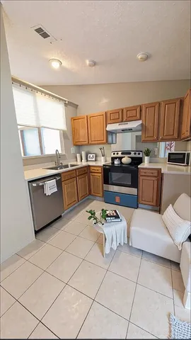 a kitchen with stainless steel appliances kitchen island granite countertop a sink dishwasher stove and refrigerator