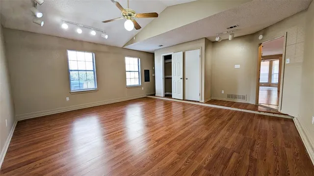 a view of an empty room with wooden floor and a window