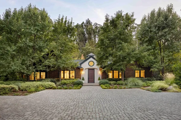 a front view of a house with a yard and a trees