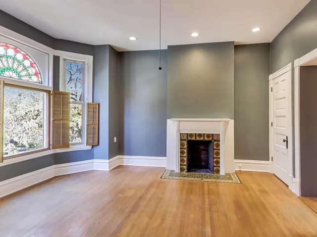 an empty room with windows and fireplace