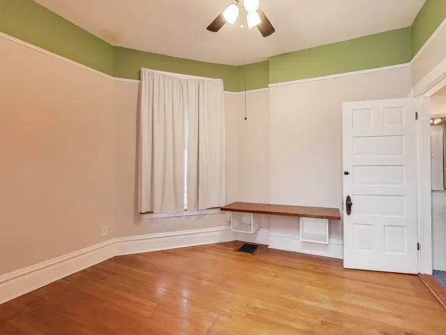 an empty room with a ceiling fan and window