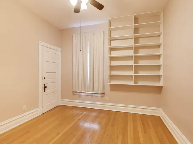 a view of an empty room with a window and wooden floor