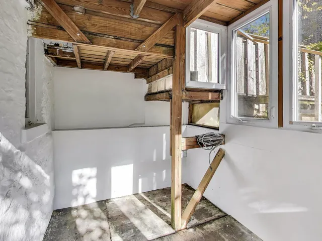 a view of a brick house with plants and large tree