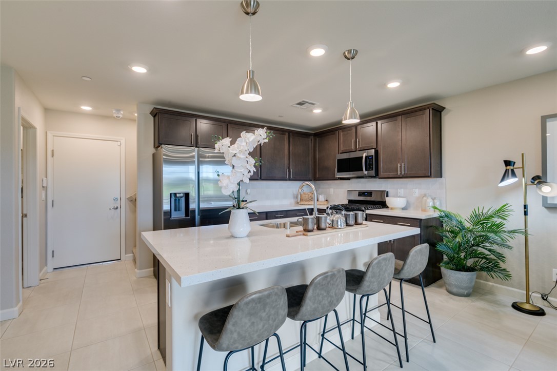 653 Pickled Pepper Place Henderson, NV 89011 - Photo 15 of 35 Culinary delights await in this modern kitchen with sleek dark cabinetry and gleaming countertops.